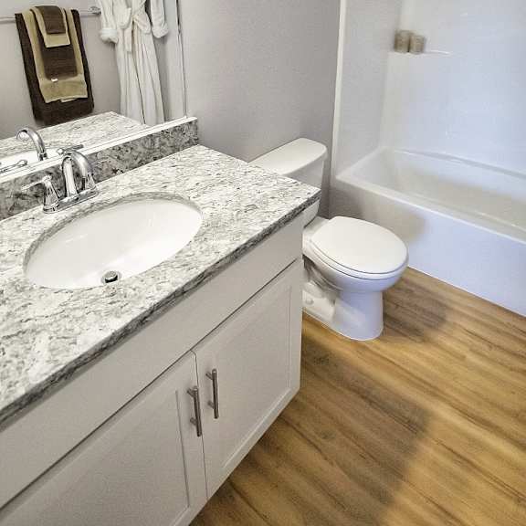 updated bathroom with granite counter and wood flooring.