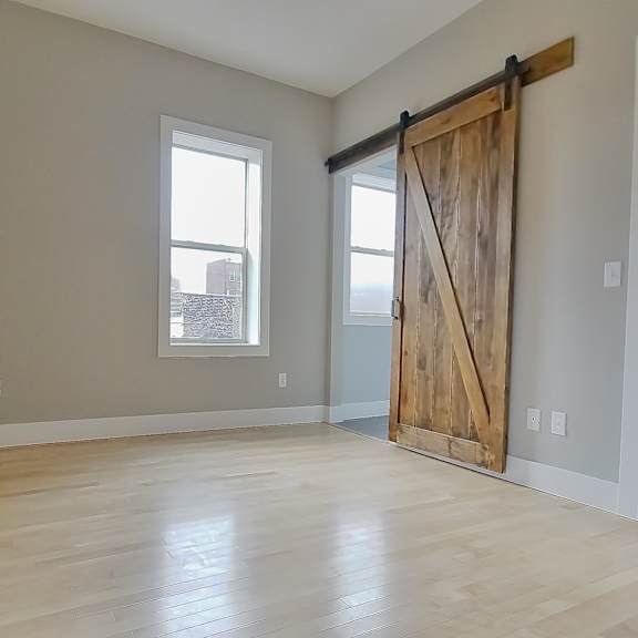 a room with a sliding barn door and a window. at integrity gold coast apartments, cleveland, ohio