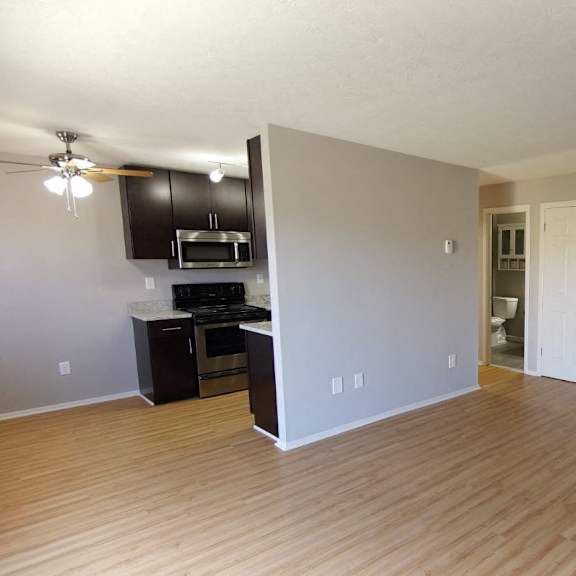 a room with plank style floors and a kitchen area with a microwave and oven.