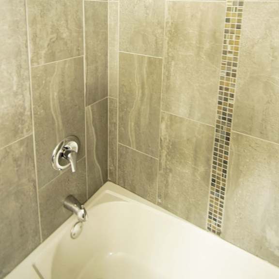 a bathroom with a tiled shower and a white bathtub.