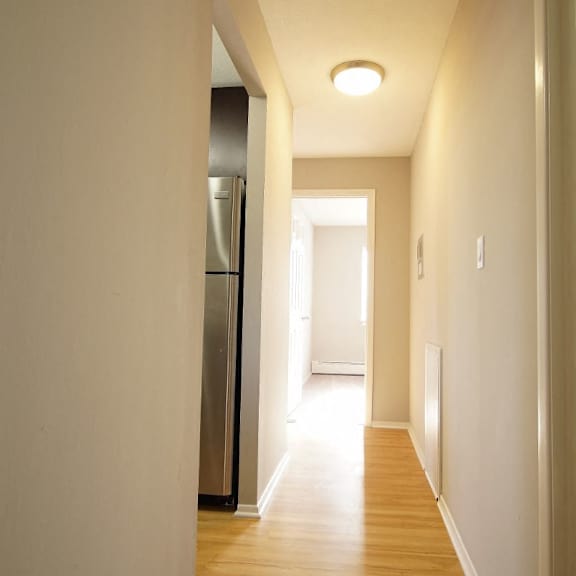 a long hallway with a refrigerator on the left side.