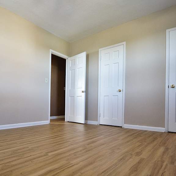 three white doors are in a room  integrity realty, cleveland, ohwith wood floors and beige walls.