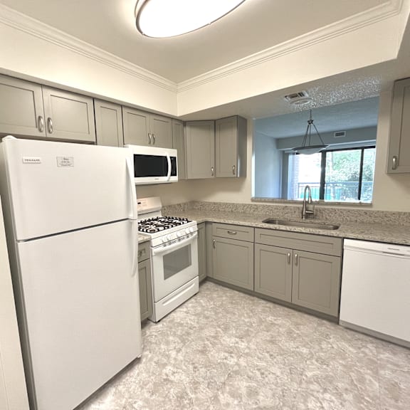a kitchen with white appliances and grey cabinets.at atrium in the village, beachwood, oh 44122