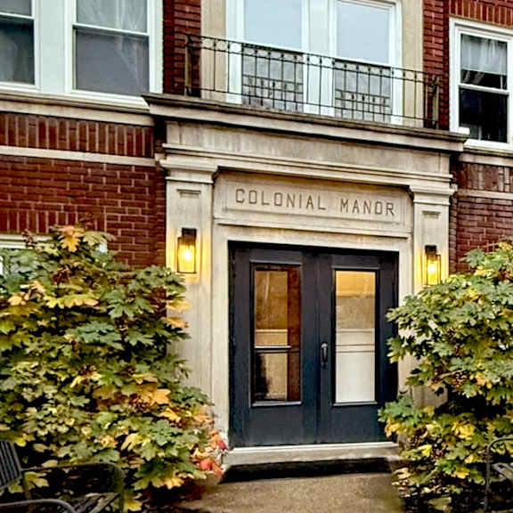 the colonial manor building has a black door and windows.