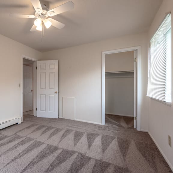 an empty living room with carpet and a ceiling fan