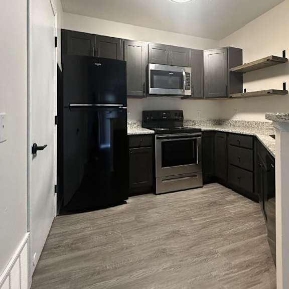 a kitchen with a black refrigerator freezer and a stove top oven