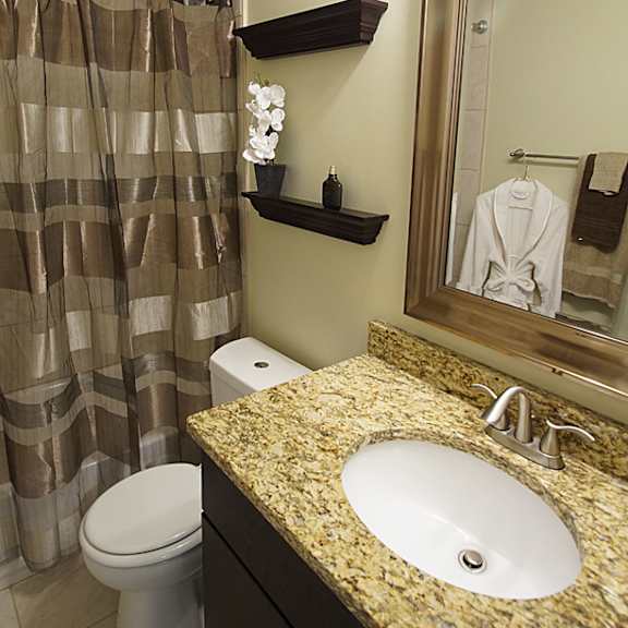 updated apartment bathroom with dark cabinets and granite counter.