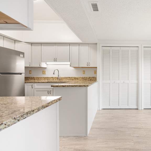 a kitchen with white cabinets and a granite countertop with a dining area.at atrium in the village, beachwood ohio
