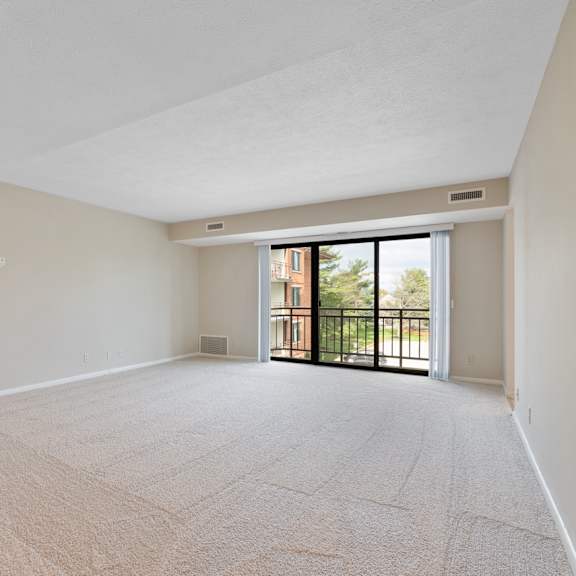 a large living room with a carpeted floor and sliding glass doors leading to a balcony.at atrium in the village, beachwood ohio