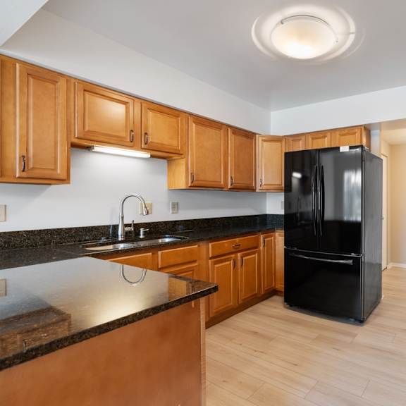 a kitchen with black appliances and wooden cabinets.at atrium in the village, beachwood, 44122