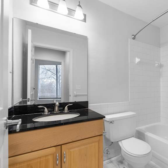white bathroom with oak cabinet and black counter at integrity medina apartments,  ohio, 44256