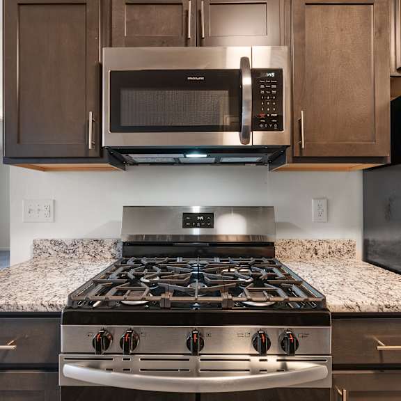 a black stove top oven with four burners and a stainless steel microwave above it at integrity medina apartments, oh, 44256