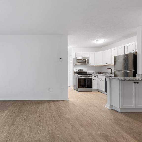 a kitchen with white cabinets and a wooden floor.