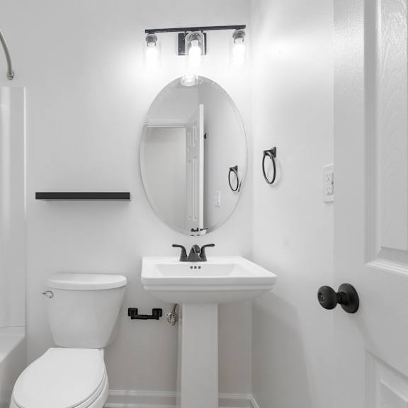 a white bathroom with a toilet, sink, and mirror.