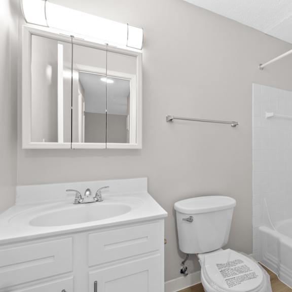 a white bathroom with a toilet, sink, and bathtub.