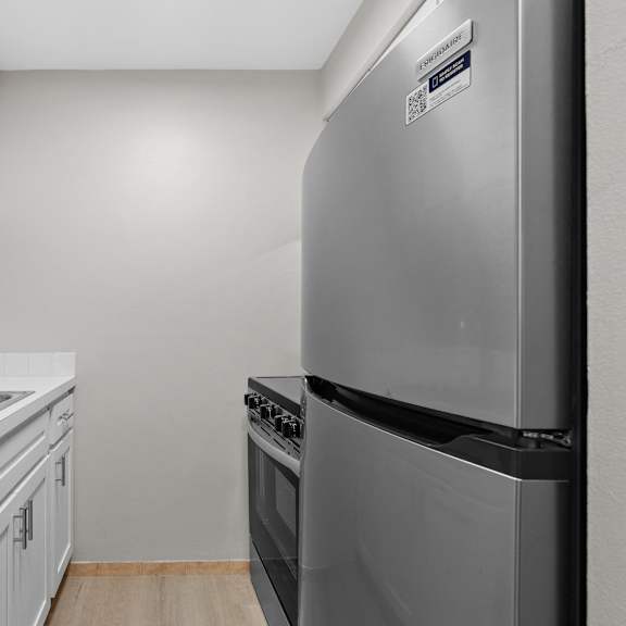 a kitchen with a stainless steel refrigerator and white cabinets.