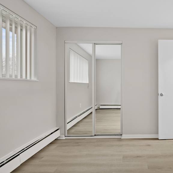 a bedroom with a mirrored closet.