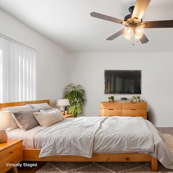 a bedroom with a bed, dresser, and ceiling fan.