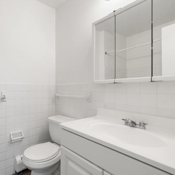 updated wynwood bathroom with white cabinets, counters, and tiling.