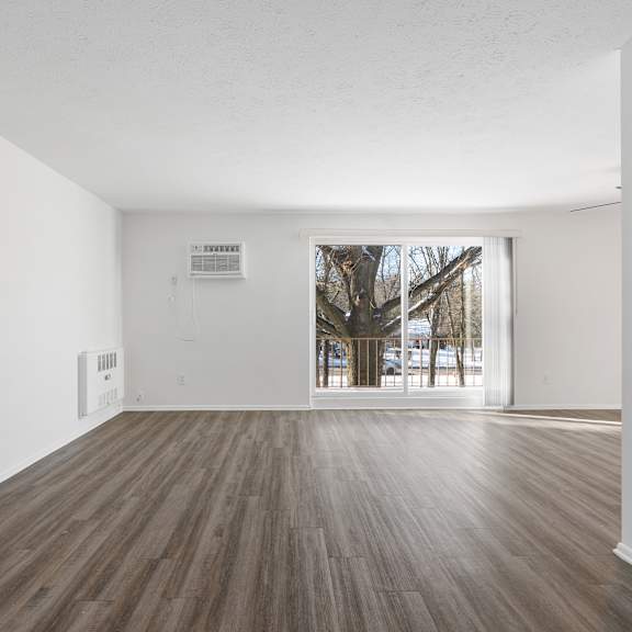 updated wynwood great room with sliding glass door to balcony and plank flooring.