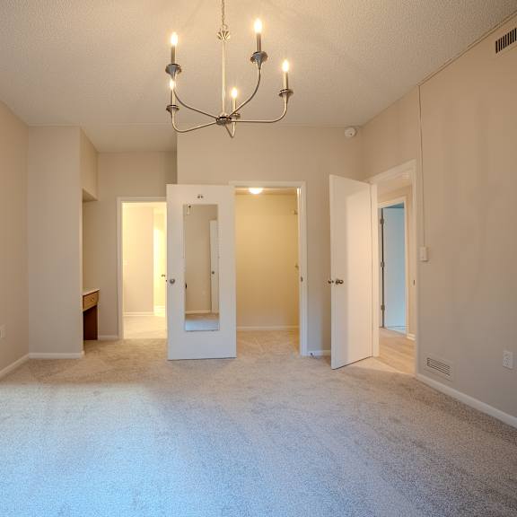 a large empty room with a chandelier and two doors.