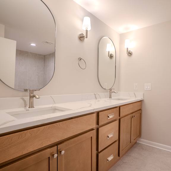 a bathroom with a white counter top and wooden cabinets.
