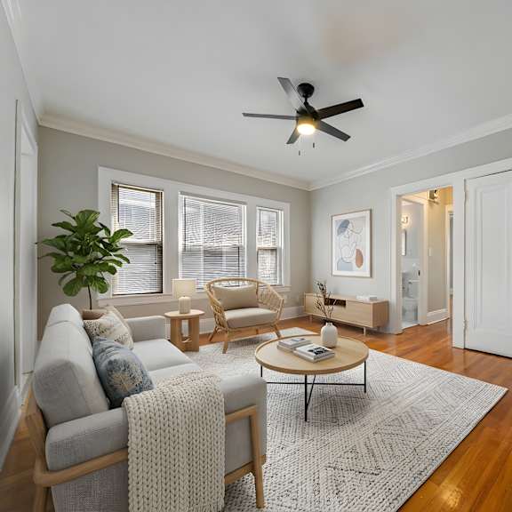 a living room with a ceiling fan and a grey sofa.