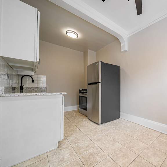 a kitchen with a refrigerator, a counter, and a fan.