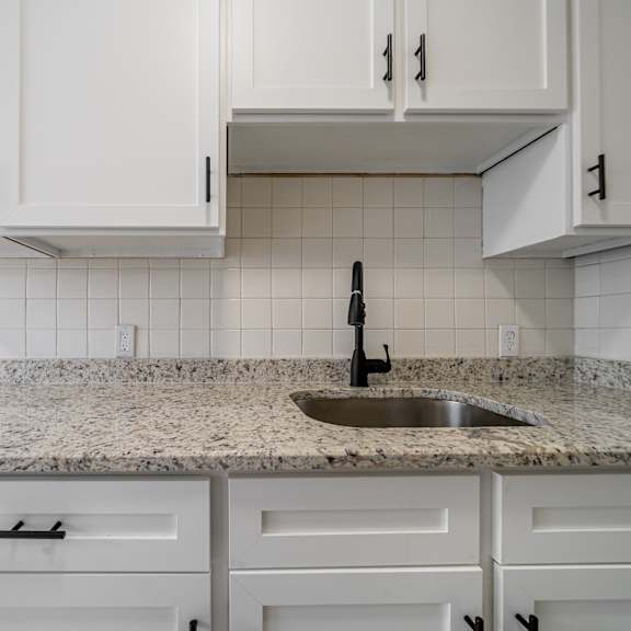a kitchen with white cabinets and a granite countertop.