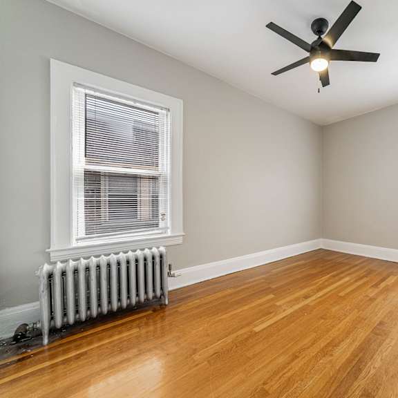 a bedroom with a bed, a ceiling fan, and a window with curtains.