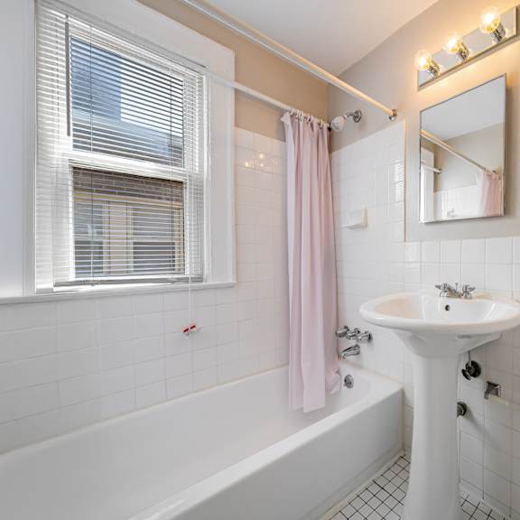 a white bathroom with a pink shower curtain.
