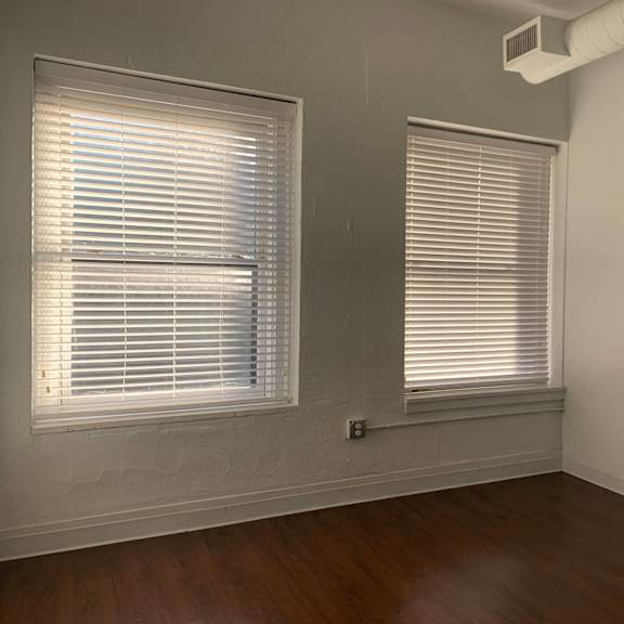 a room with two windows covered in white blinds.