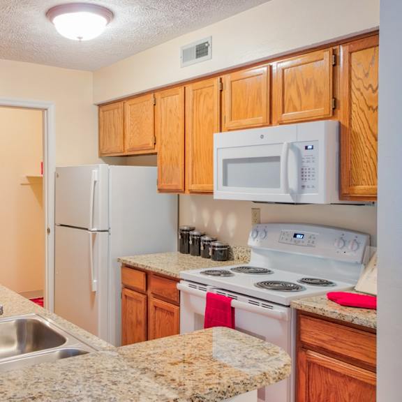 traditional kitchen with white appliances and wood cabinetry at hunt club apartments, copley, 44321