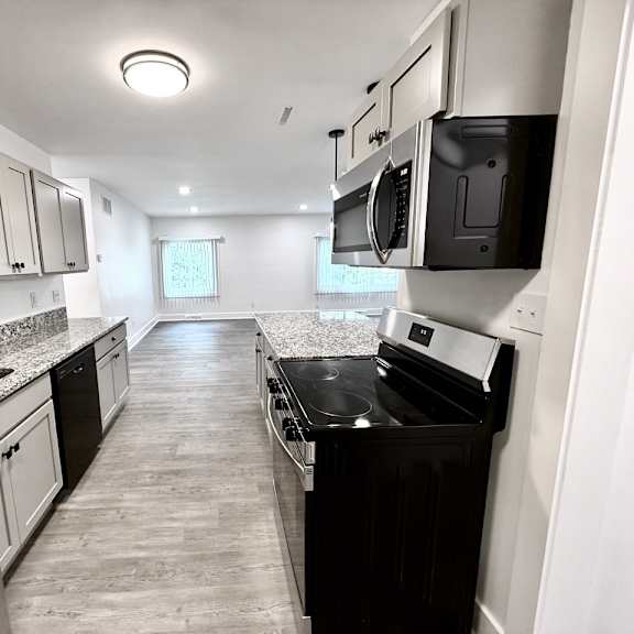 a modern kitchen with stainless steel appliances and black countertops old green place apartments, beachwood, oh