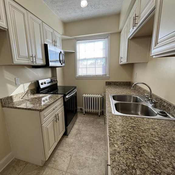 an updated galley  kitchen with granite countertops and a window integrity realty, cleveland