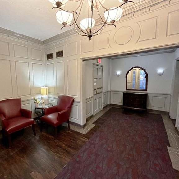 a room with a chandelier, two red chairs, and a table with a vase of flowers integrity realty, cleveland, ohio