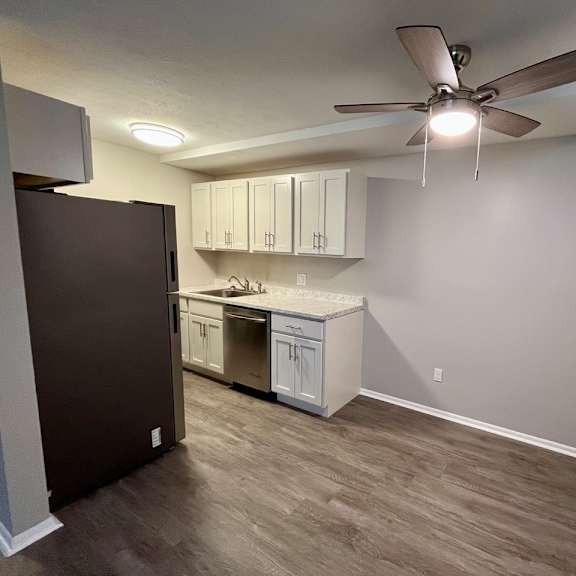 an empty room with a kitchen and a ceiling fan