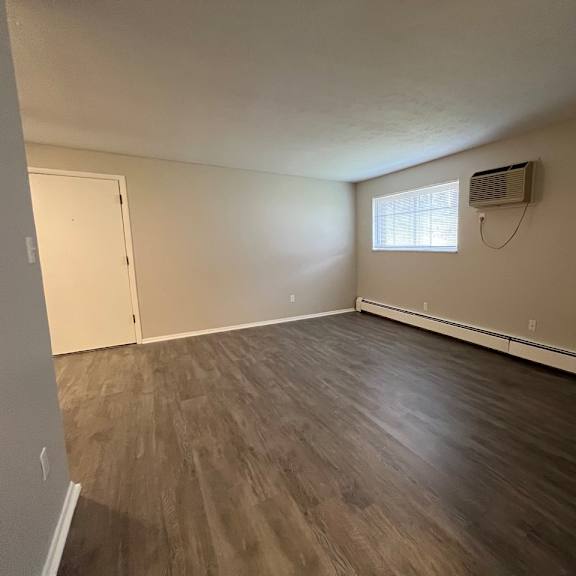 an empty living room with wood floors and an air conditioner