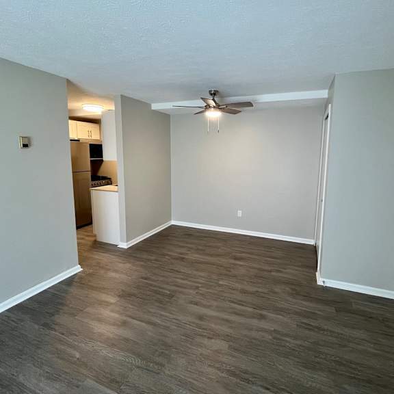 an empty living room with wood flooring and a ceiling fan