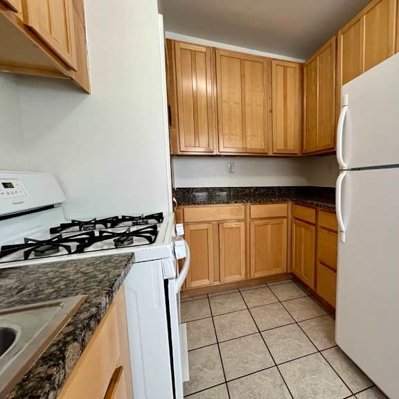 empty kitchen with white appliances and wooden cabinets at integrity cleveland heights, cleveland heights, 44106