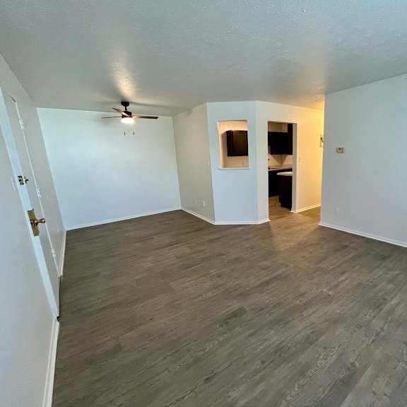 an empty living room with plank flooring and a ceiling fan
