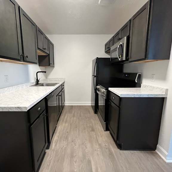 an empty kitchen with black appliances and white marble counter tops