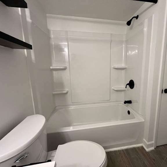 a white bathroom with a toilet and a tub