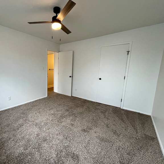 a room with a ceiling fan and carpeted floor.