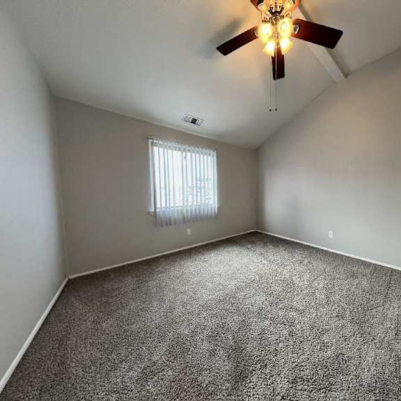 an empty room with a ceiling fan and a window