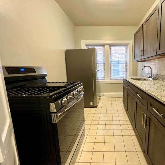 mapleview kitchen with espresso cabinets, tile flooring, and granite counters.
