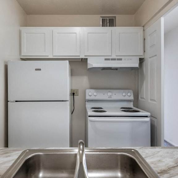 a kitchen with white appliances and white cabinets and a sink