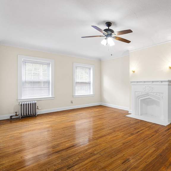 a living room with wood floors, a fireplace, and a ceiling fan