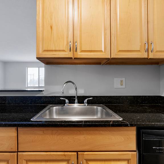 a kitchen with wooden cabinets and a black countertop at integrity medina apartments, medina, oh,  44256