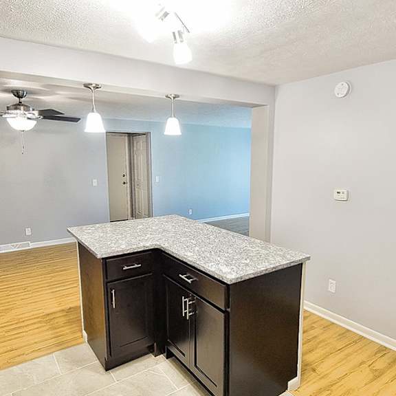 a kitchen with a refrigerator, island, and ceiling fan.